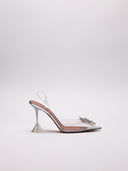 Immagine di scarpe slingback Amina Muaddi Begum in PVC trasparente con decori gioiello, su sfondo neutro.