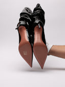 Stivaletto Amina Muaddi Jahleel in vernice nera, vista suole leggermente rovinate, design elegante e slouchy.