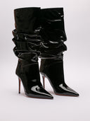 Stivaletto Amina Muaddi Jahleel in vernice nera, vista suole leggermente rovinate, design elegante e slouchy.