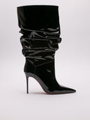 Stivaletto Amina Muaddi Jahleel in vernice nera, vista suole leggermente rovinate, design elegante e slouchy.