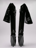 Immagine di stivali Amina Muaddi in latex nero, tacco alto e design lucido.