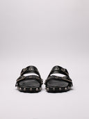 Vista frontale dei sandali Balenciaga in pelle nera con fibbie e borchie argentate.