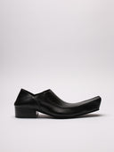 Immagine di scarpe Balenciaga in pelle nera con vista suola ruvida e dettaglio di segno sulla scarpa destra