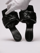 Vista del sandalo Bottega Veneta in pelle nera intrecciata, dettagli su tacco e struttura.