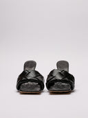 Vista frontale del sandalo Bottega Veneta in pelle nera intrecciata, dettagli su tacco e struttura.