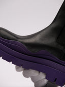 Stivali Bottega Veneta in pelle nera con suola viola, vista laterale e frontale.