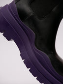 Stivali Bottega Veneta in pelle nera con suola viola, vista laterale e frontale.