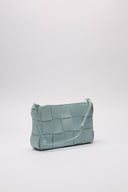 Borsa in pelle intrecciata di colore azzurro, vista laterale, evidenziata da dettagli artigianali.