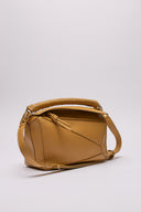 Vista frontale,diagonale e dettagliata della LOEWE Puzzle Bag in pelle color neutro, con micro segni impercettibili.