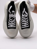 Sneakers alte di MCQUEEN in tela nera con suola bianca robusta, dettaglio frontale