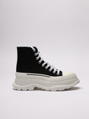 Sneakers alte di MCQUEEN in tela nera con suola bianca robusta, dettagli logo laterale.