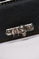 Clutch MCQUEEN in denim con dettagli decorativi a teschio e chiusura iconica.