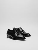 Scarpe derby in pelle lucida nera, vista frontale e laterale.