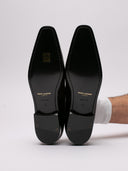 Raffinate slippers Saint Laurent in vernice nera con dettaglio elegante.