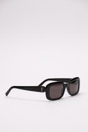 Occhiali da sole SAINT LAURENT in acetato nero con lenti scure e logo YSL laterale.